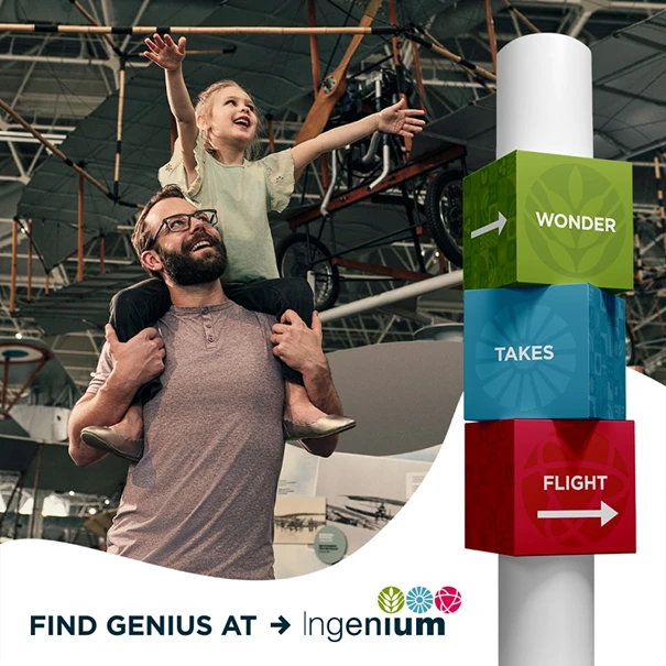 A child on a parent’s shoulders beside Ingenium wayfinding cubes